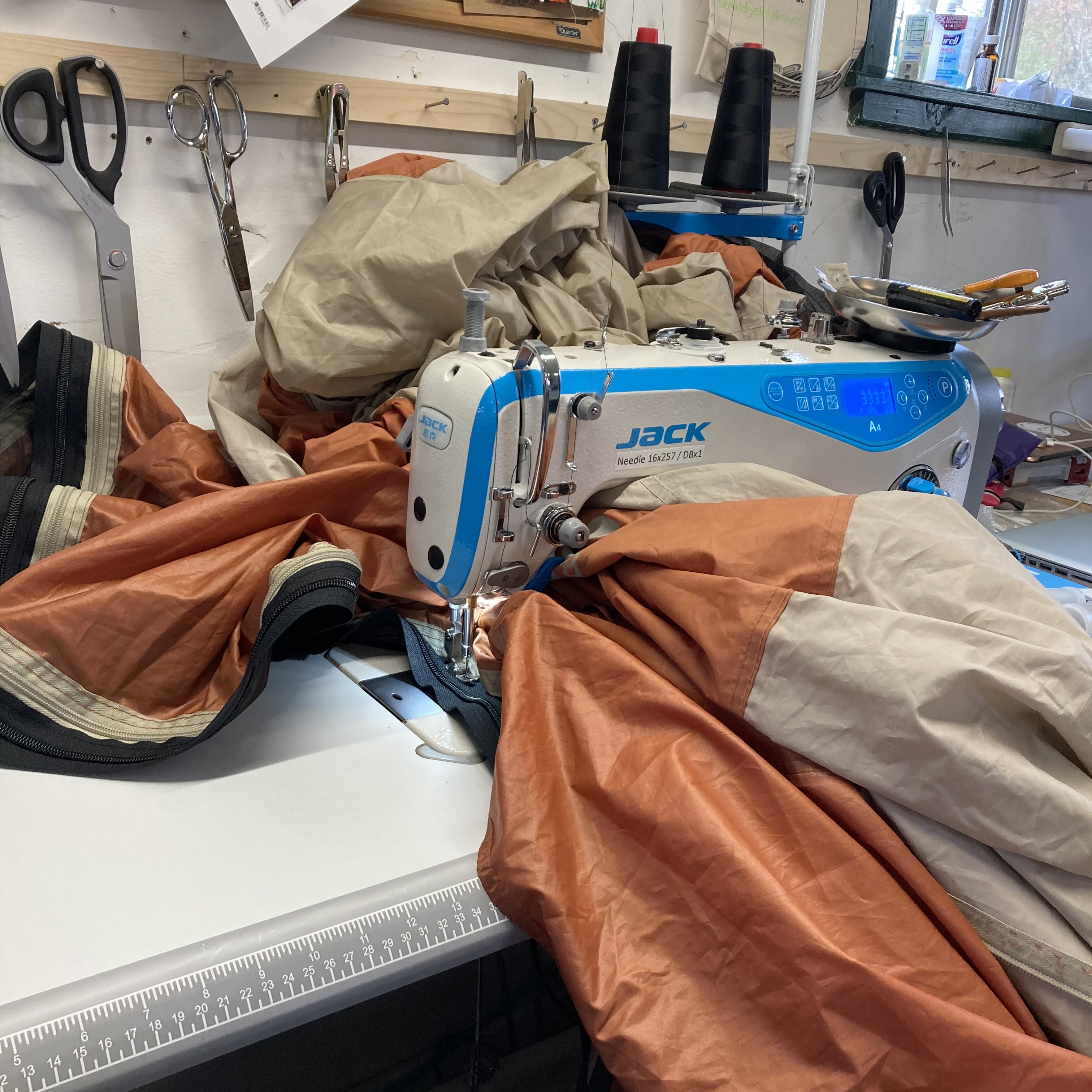An image of a tan and orange tent under a sewing machine for a zipper replacement.